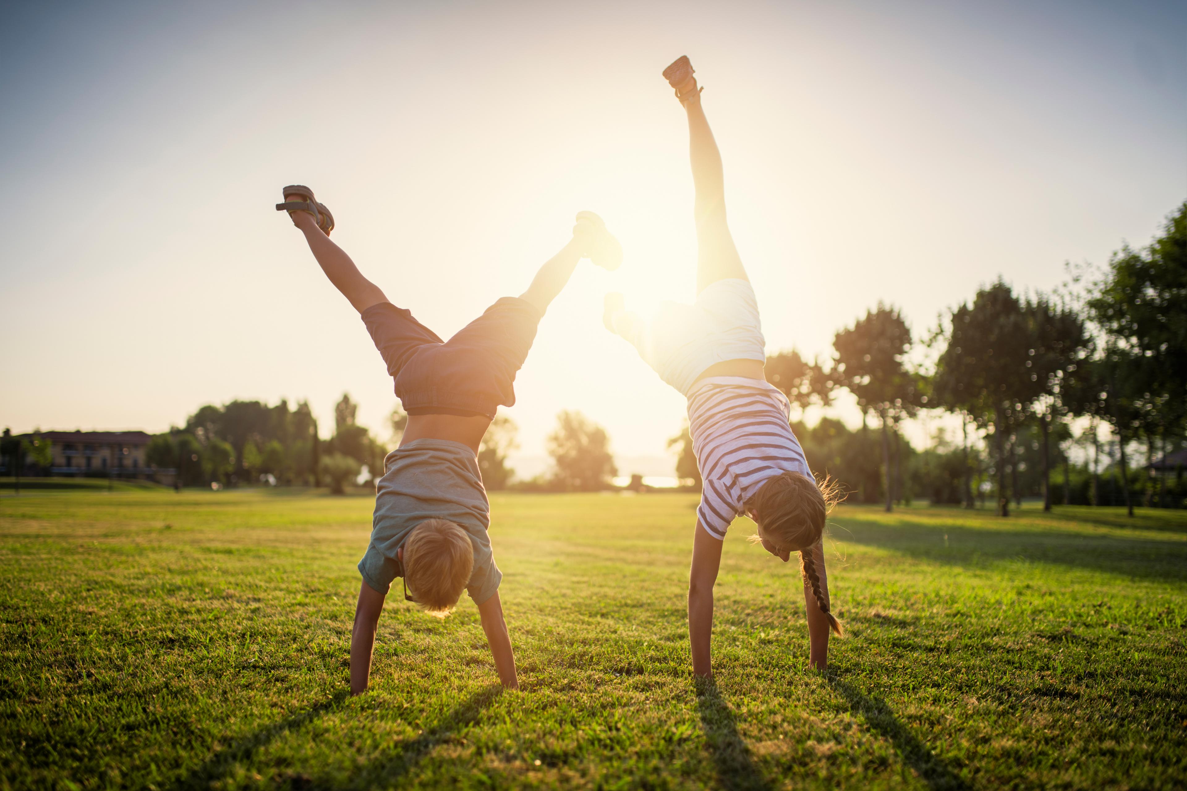 Two kids doing handstands on the grass
